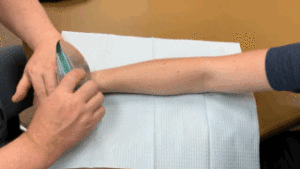 A man is applying a bandage to his arm.