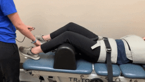 A woman is receiving traction therapy from a physical therapist.