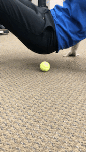 A person doing a push up at home with a tennis ball.