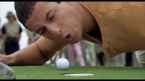 A man leaning over a golf ball on the green.